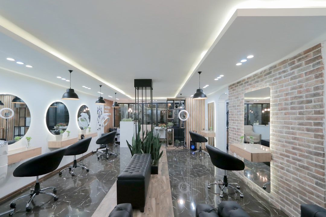 A modern hair salon with black chairs, round mirrors, and a brick wall